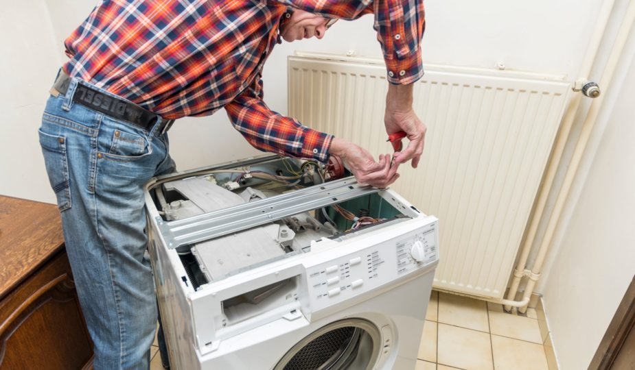Middle aged man repairing broken washing machine with tools, household chores